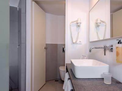 Salle de bain d'hôtel moderne avec lavabo rectangulaire, porte-serviettes et sèche-cheveux.