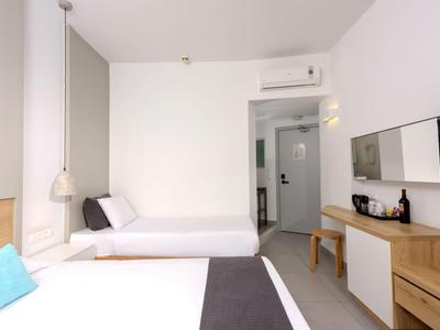 Chambre d'hôtel moderne avec deux lits, bureau et télévision.