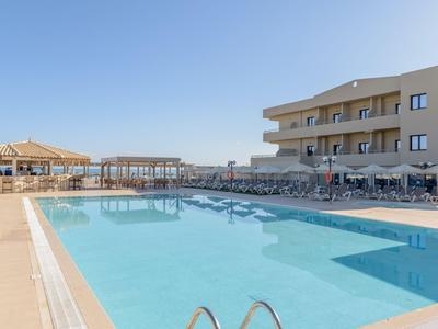 Moderner Hotelpool mit Liegestühlen und klar blauem Wasser unter hellem Himmel.