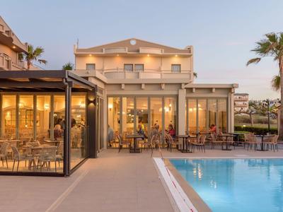 Modernes Hotel mit Pool und Sitzbereichen bei Sonnenuntergang unter blauem Himmel.