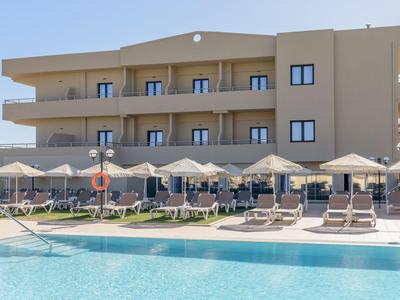 Moderner Hotelkomplex mit Pool, Sonnenschirmen und Liegestühlen unter klarem Himmel.