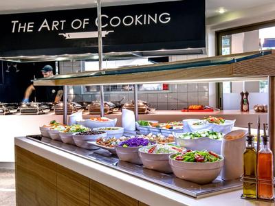 Buffetstation mit verschiedenen Salaten und Ölen in einem modernen Restaurantbereich.