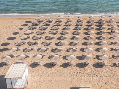 Pláž s mnoha slunečníky uspořádanými v řadách a malou bílou chatkou