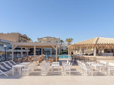 Moderner Außenbereich mit Pool, Sonnenliegen und einer Bar unter klarem Himmel.