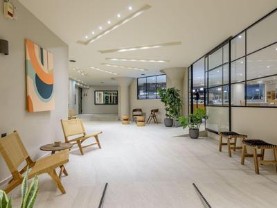 Heller, moderner Hotel-Warteraum mit Holzstühlen und Kunst an der Wand.