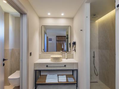 Moderní hotelová koupelna se zrcadlem, umyvadlem, ručníky a sprchou.