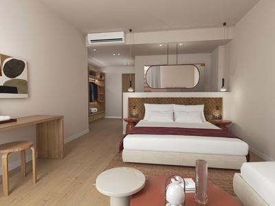 Moderní hotelový pokoj s manželskou postelí, psacím stolem, posezením a neutrálními barvami.