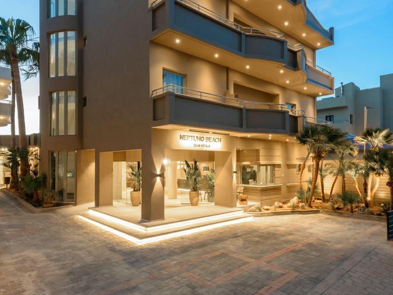 Moderní třípatrová budova hotelu se osvětleným vstupem za soumraku.