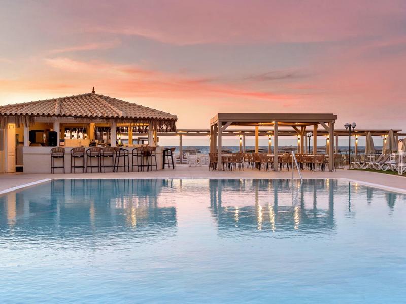 Bazén s barem a venkovním posezením při západu slunce.