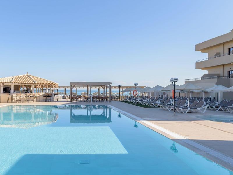 Čistý bazén s lehátky a výhledem na moře pod slunečnou oblohou