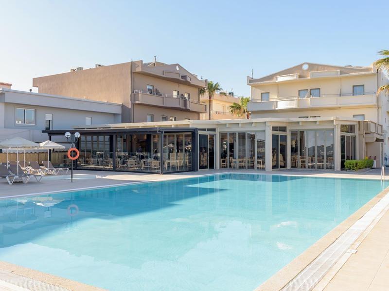 Moderní hotelový bazén s terasou a lehátky pod jasnou oblohou