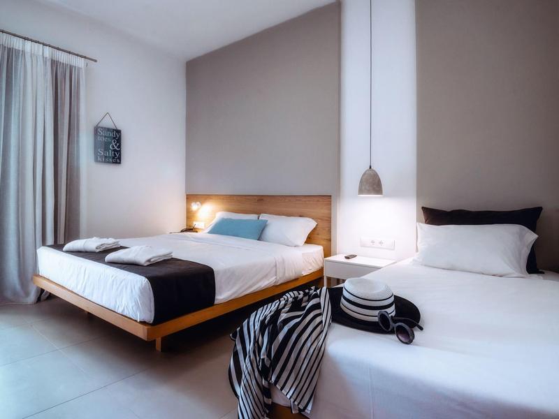 Moderní hotelový pokoj se dvěma postelemi, nočním stolkem a minimalistickým zařízením.