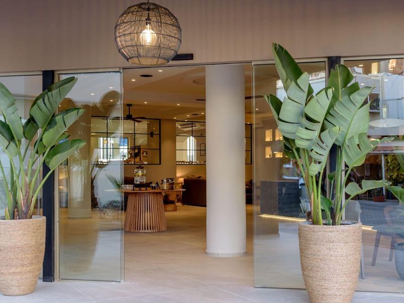 Moderní hotelový vchod s velkými skleněnými dveřmi a dvěma velkými květináči po stranách
