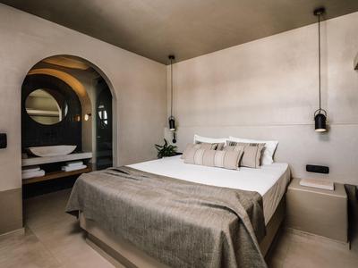 Nowoczesny pokój hotelowy z dużym łóżkiem i otwartą łazienką z umywalkami.