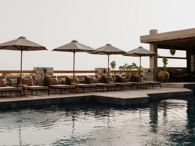 Strefa basenowa z leżakami i parasolami w ośrodku podczas zachodu słońca.