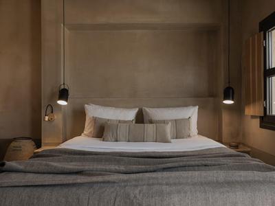 Gezellige hotelkamer met een groot bed, neutrale tinten, twee nachtlampen en een raam aan de rechterkant.