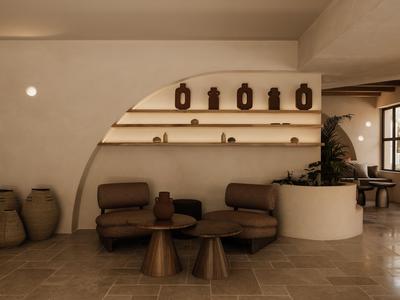 Nowoczesny, przytulny kącik wypoczynkowy z brązowymi fotelami, stolikami i dekoracyjnymi wazonami w pokoju hotelowym.