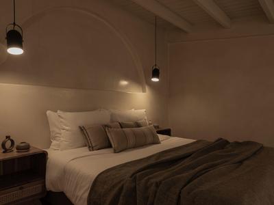 Gezellige hotelkamer met groot bed, kussens en warm licht.