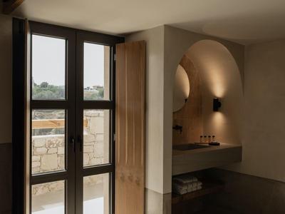 Moderne hotelkamer met groot raam, natuurlijk licht en minimalistisch wastafelgebied.