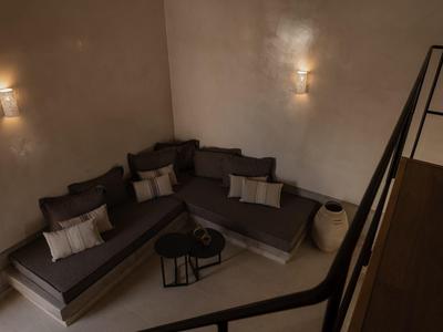 Gezellige zithoek met bank, kussens en gedimde verlichting in een hotelkamer.