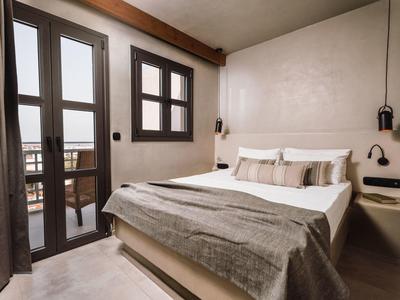 Gezellige slaapkamer met tweepersoonsbed, beige muren en balkon via glazen deuren.