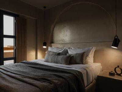 Gezellig bed met meerdere kussens en een stoffen deken in een modern, sfeervol verlicht slaapkamer.