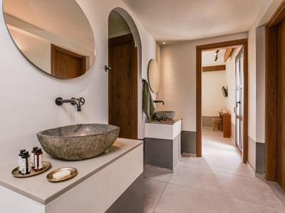 Moderne lichte gang met twee stenen wastafels en een ronde spiegel aan de muur