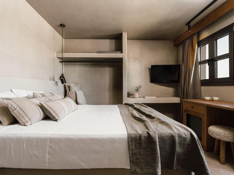 Gezellige hotelkamer met tweepersoonsbed, zachte verlichting, bureau, tv en moderne, neutrale inrichting.