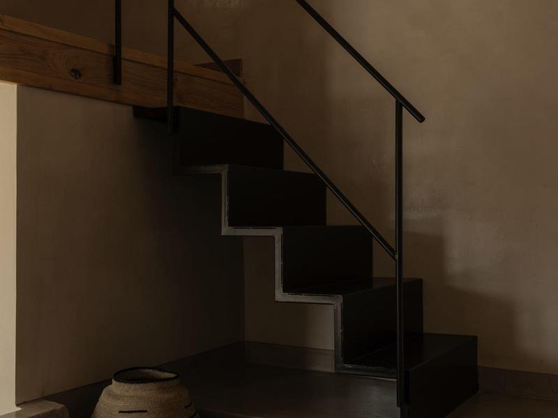 Moderne zwarte trap met smeedijzeren leuning en decoratieve manden eronder naast het raam.