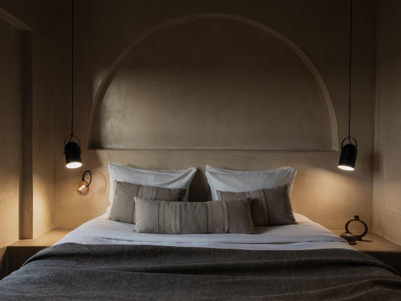 Gezellige hotelkamer met een tweepersoonsbed, grijze beddengoed en moderne bedlampen.