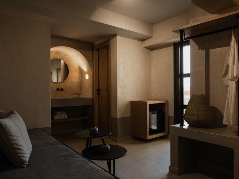 Gezellige hotelkamer met zithoek, open badkamer en natuurlijk licht.