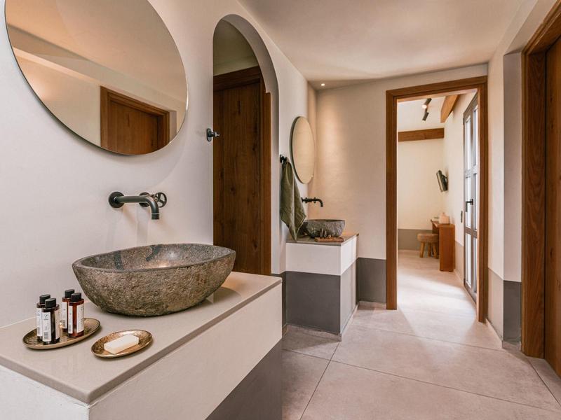 Moderne lichte gang met twee stenen wastafels en een ronde spiegel aan de muur