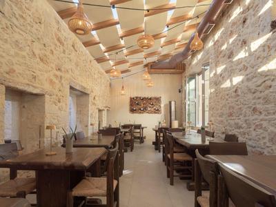 Salle à manger rustique avec murs en pierre et mobilier en bois, éclairée par la lumière naturelle.