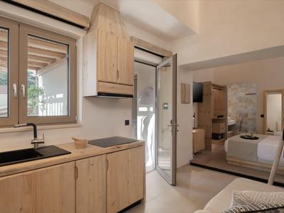 Coin de pièce lumineux avec armoires en bois, fenêtre, porte vers la terrasse et vue sur la chambre.