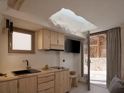 Petite kitchenette avec armoires en bois, évier, télévision et accès à un espace extérieur.