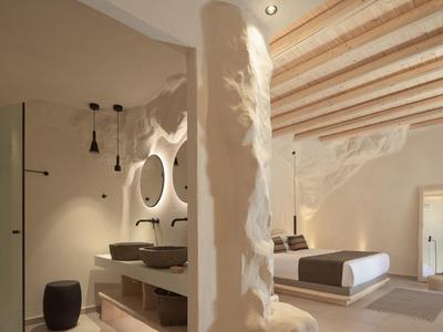 Chambre moderne avec plafond en bois, grand lit et décorations élégantes sous une lumière chaude.