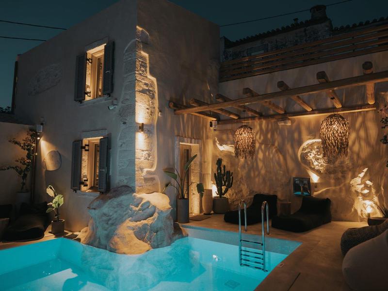 Éclairage d'ambiance d'une piscine et d'une terrasse dans un bâtiment traditionnel la nuit.