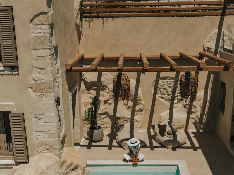 Cour avec pergola, coin salon et petite piscine par une journée ensoleillée.
