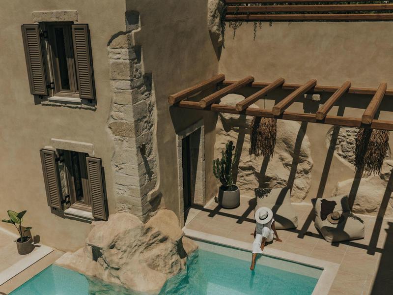 Vue d'une petite piscine à côté d'un bâtiment avec des poutres et une personne sautant dans l'eau.