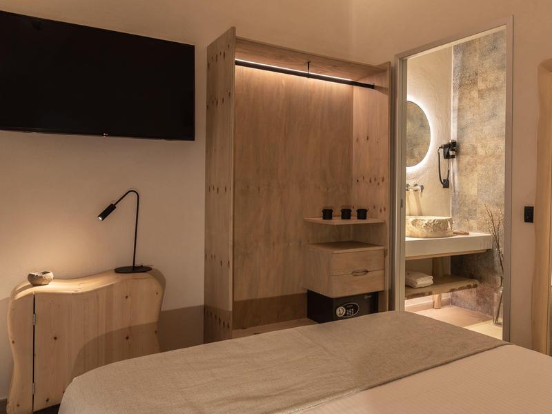 Chambre d'hôtel confortable avec télévision, armoire en bois et salle de bains moderne.