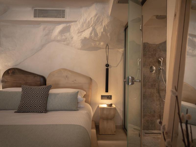 Chambre d'hôtel confortable avec lit double, coussins et éclairage doux aux teintes chaudes.