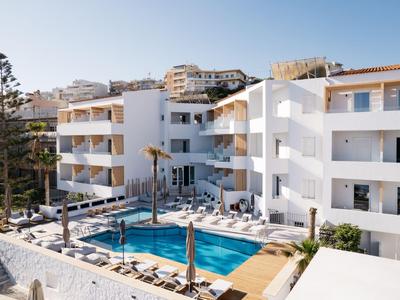 Nowoczesny kompleks hotelowy z wieloma piętrami, basenem i leżakami.