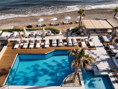 Widok z lotu ptaka na basen z leżakami i bezpośrednim dostępem do plaży i morza.