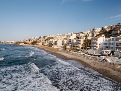 Wybrzeże z piaszczystą plażą i wieloma białymi budynkami wzdłuż morza pod czystym niebem.