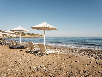 Puste leżaki z parasolami na spokojnej kamienistej plaży pod czystym niebem.