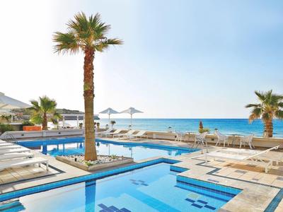 Strefa basenu z palmami i widokiem na morze w słoneczny dzień.