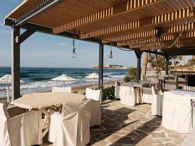 Restauracja na świeżym powietrzu z zadaszonymi stolikami z widokiem na morze w słoneczną pogodę