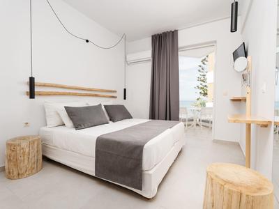 Nowoczesny pokój hotelowy z podwójnym łóżkiem, drewnianymi akcentami i widokiem na taras w świetle dziennym.