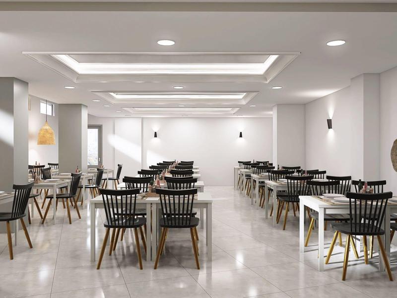 Nowoczesna, jasna restauracja z czarnymi krzesłami i drewnianymi stołami w neutralnym pomieszczeniu.