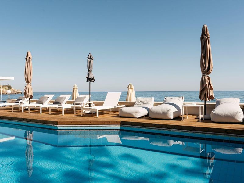 Luksusowy basen z leżakami i parasolami przy morzu pod czystym niebem.